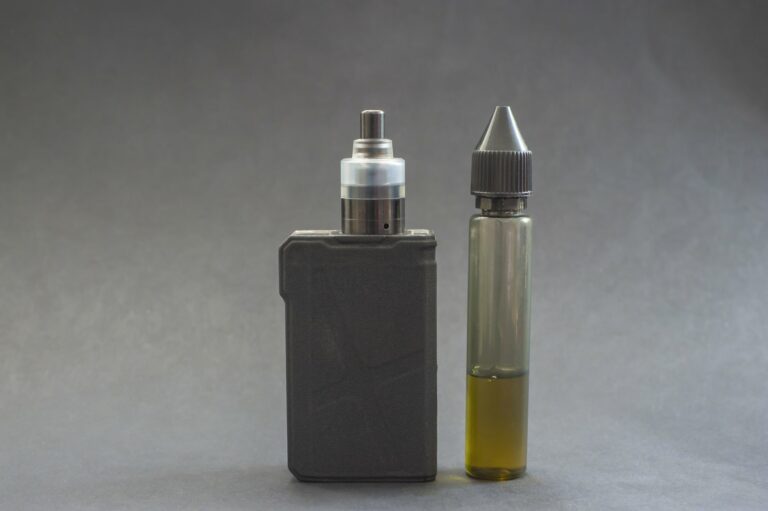 Ein Verdampfergerät links, daneben eine Flasche mit E-Liquid in einer transparenten Verpackung.