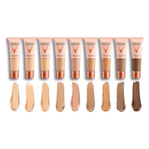 Verschiedene Farbnuancen von Vichy Make-up in Tuben, mit passenden Farbpigmenten auf einem weißen Hintergrund.